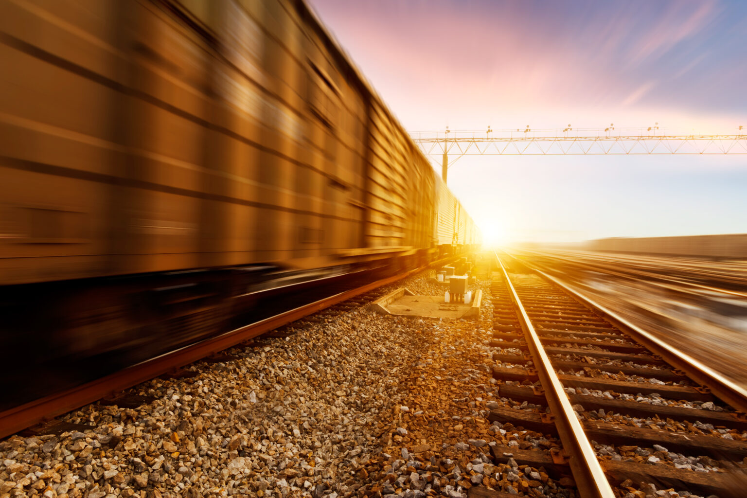 Containerzug fährt schnell in den Sonnenuntergang