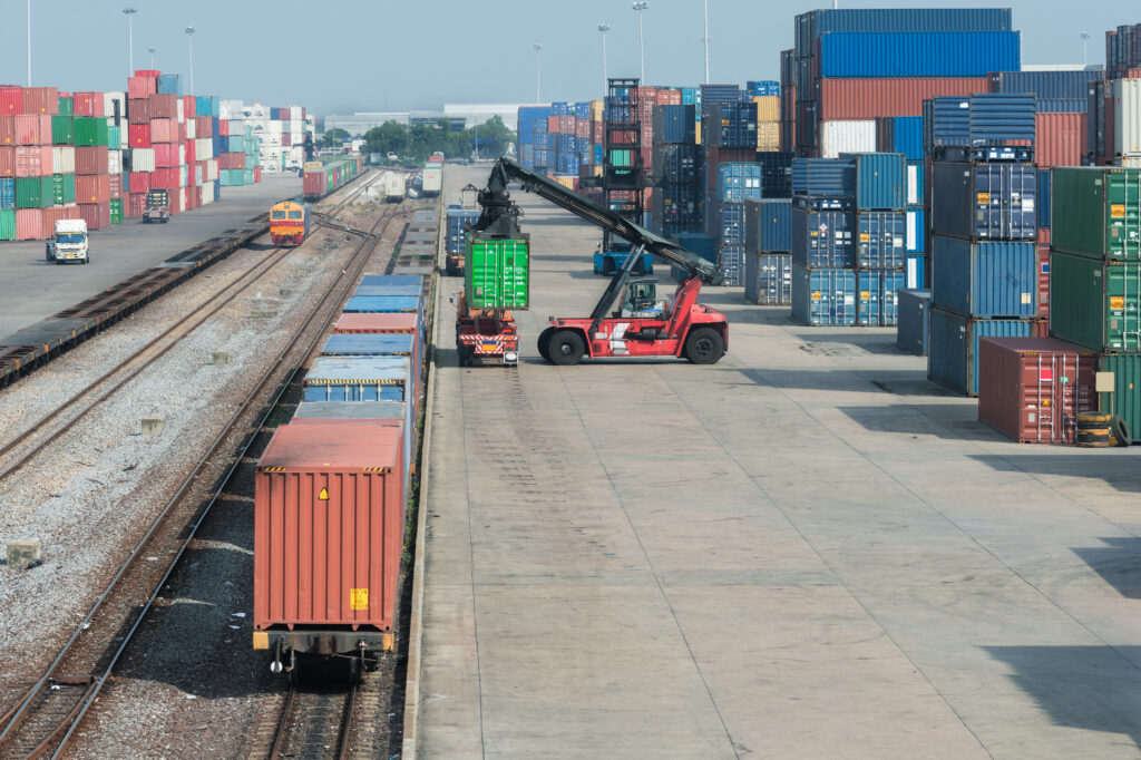 Kran hebt Container vom Wagen auf den Zug