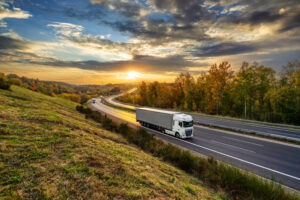Ein großer LKW fährt im Sonnenuntergang über die Autobahn