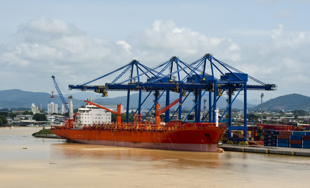 Grosses Containerschiff liegt an der Containerbruecke am Kai im Hafen